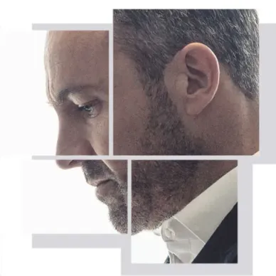 Hombre de perfil con pelo corto y barba, vestido con traje y expresión seria