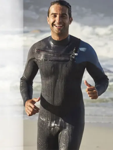 Athletic man in a wetsuit coming out of the sea