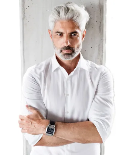 Man with white hair and beard wearing a casual white shirt
